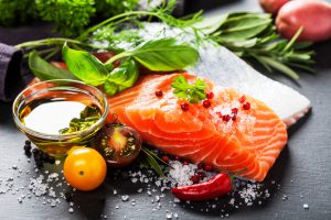 Delicious portion of fresh salmon fillet with aromatic herbs, spices and vegetables - healthy food, diet or cooking concept